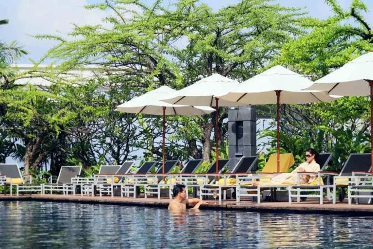 Outdoor Swimming Pool Area with Lounge Chairs and Umbrellas in Pathumwan Bangkok