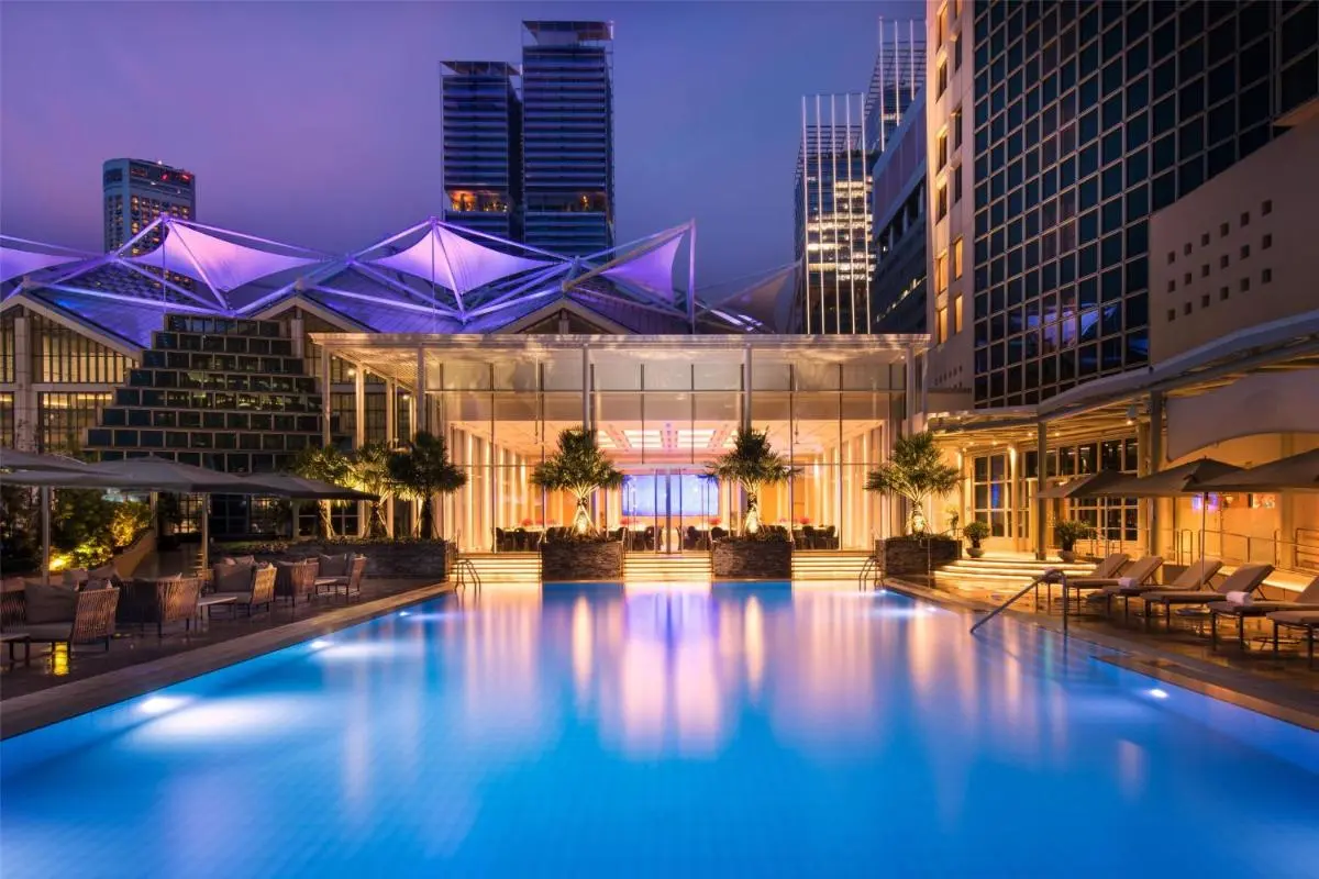 Outdoor Swimming Pool Area with Lounge Chairs and Urban Skyline at Marina Bay