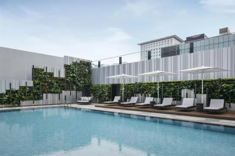 Outdoor Swimming Pool Area with Lounge Chairs and Vertical Gardens in Orchard Singapore