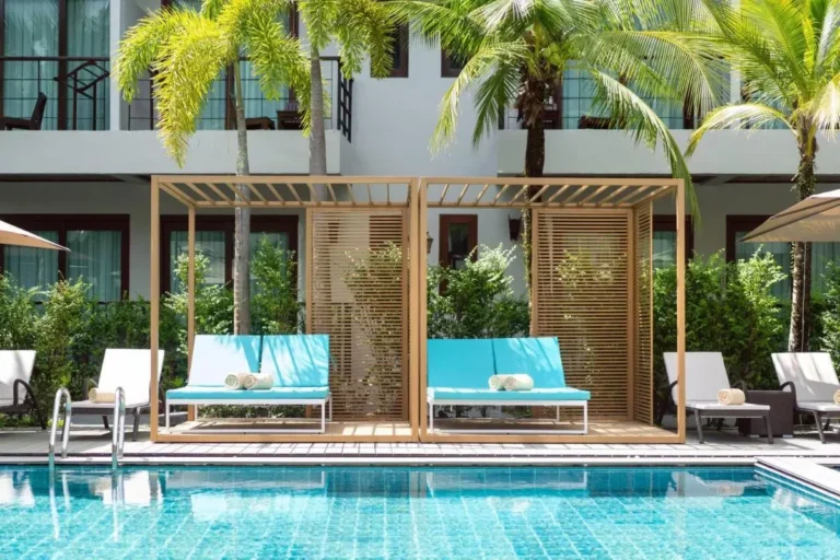 Outdoor Swimming Pool Area with Wooden Cabanas and Lounge Chairs in Thalang