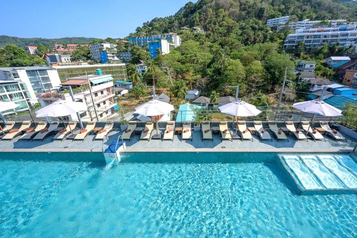 Outdoor Swimming Pool with Lounge Chairs and Umbrellas Overlooking Patong Beach Hillside