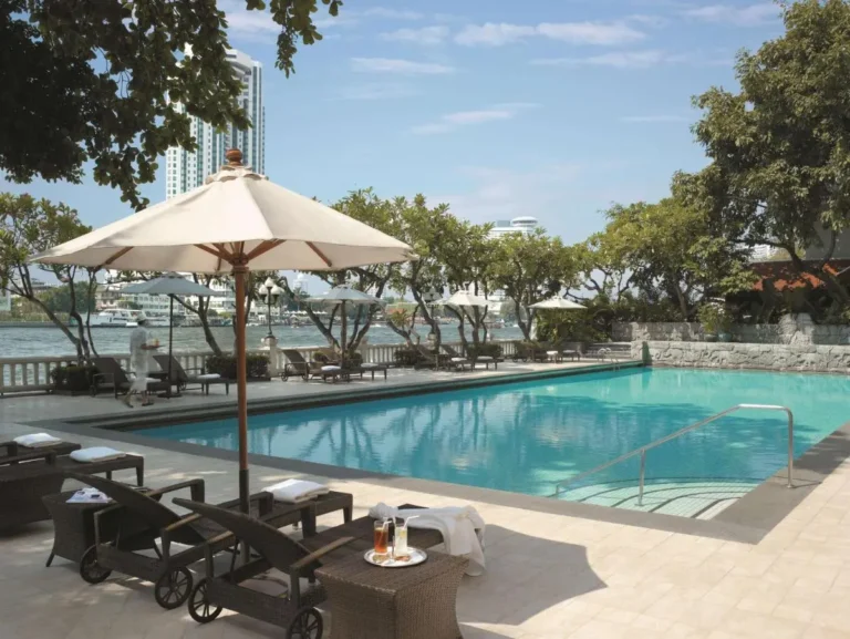 Outdoor Swimming Pool with Lounge Chairs and Waterfront View in Bang Rak