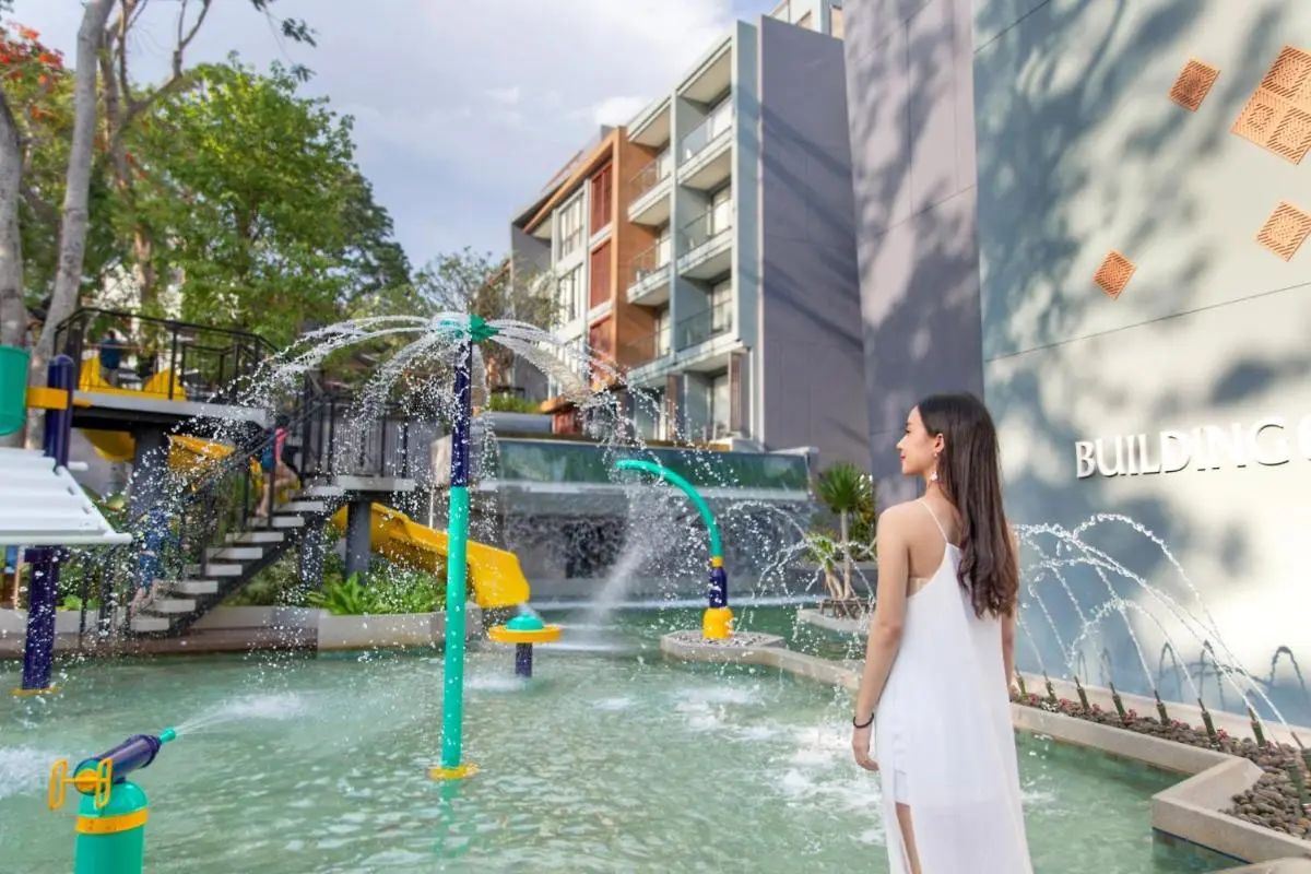 Outdoor Water Play Area with Jets and Yellow Slide Near Multi-Story Building at Patong Beach