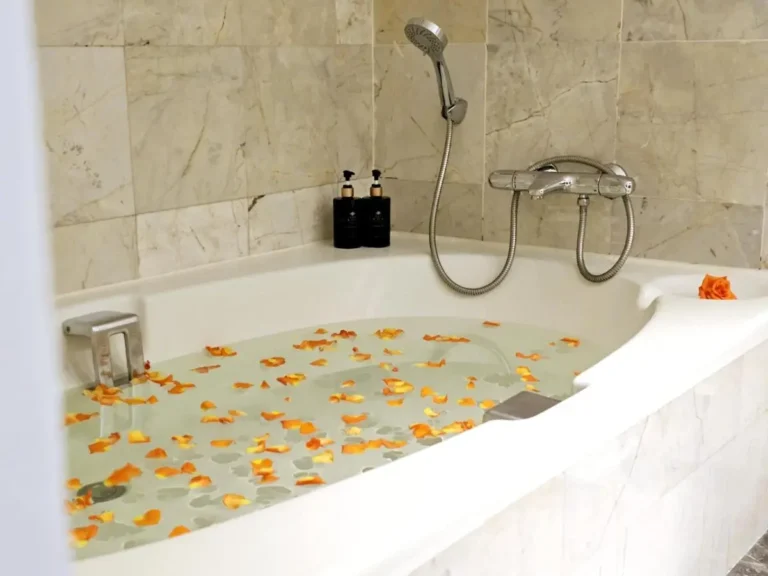 Relaxing Bathtub with Orange Flower Petals and Chrome Faucet in Ratchathewi Bathroom
