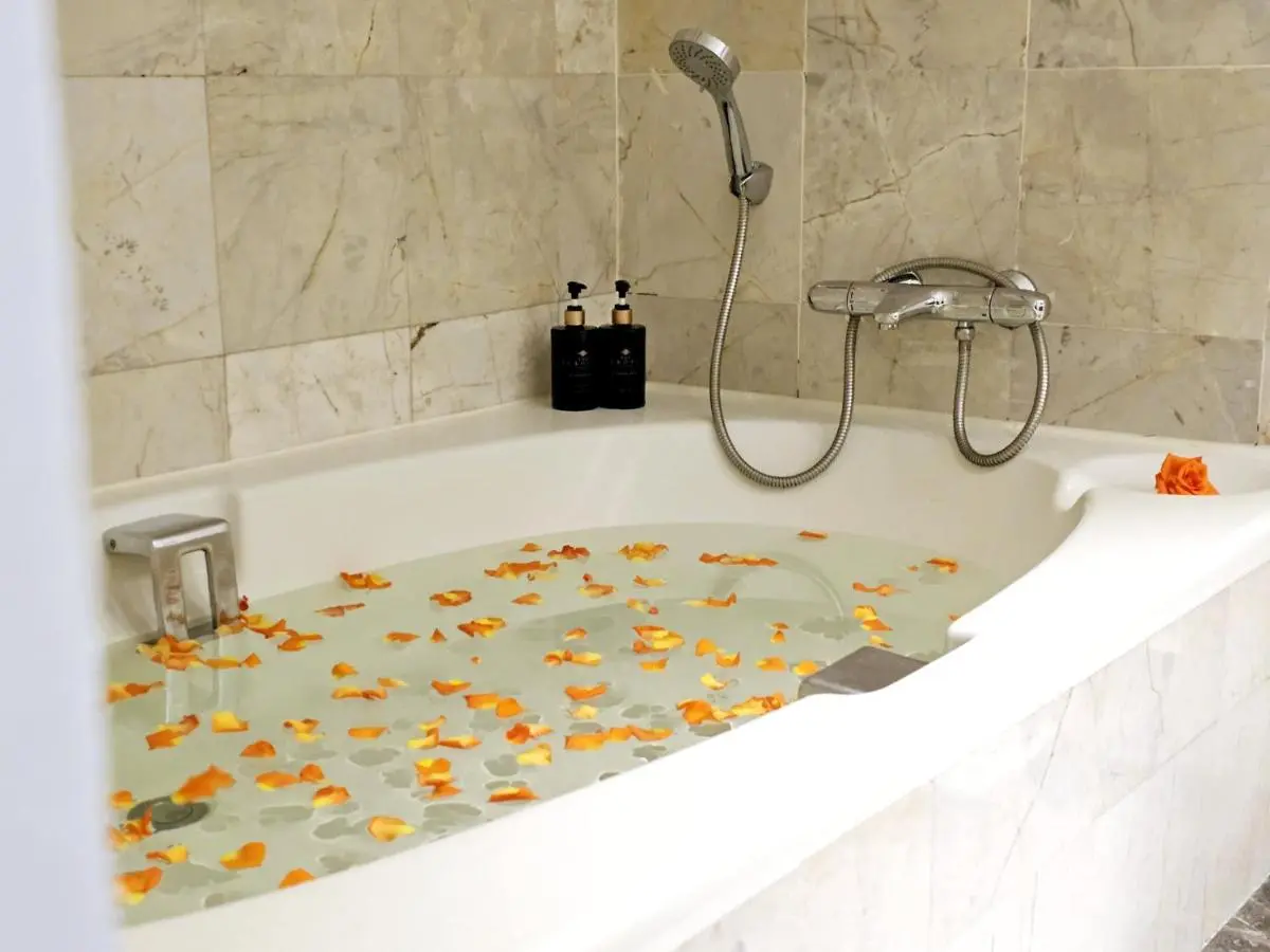 Relaxing Bathtub with Orange Flower Petals and Chrome Faucet in Ratchathewi Bathroom