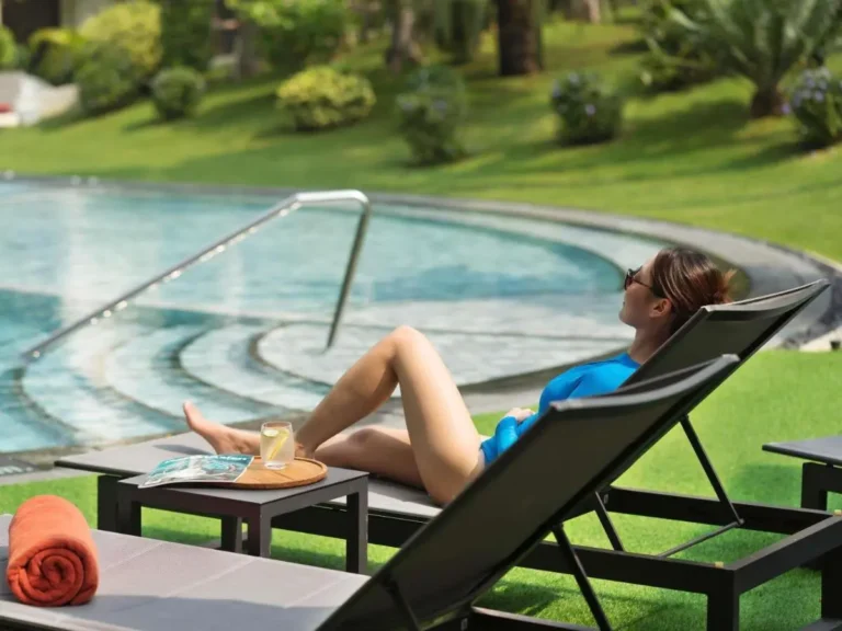 Relaxing Outdoor Pool Area with Lounge Chairs and Clear Beverage in Pathumwan Bangkok