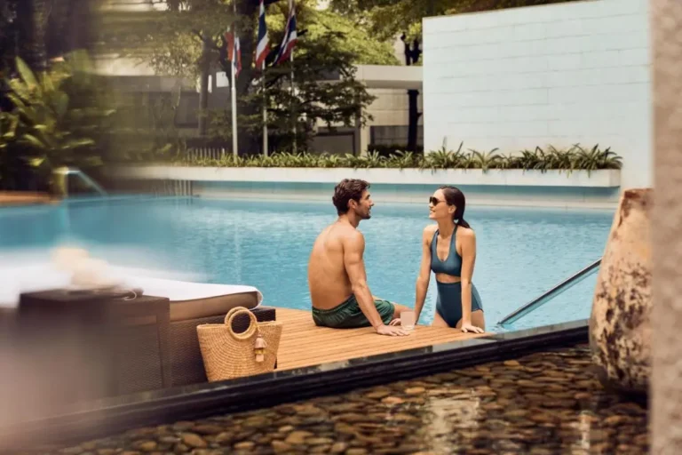 Relaxing Outdoor Swimming Pool Area with Wooden Deck and Water Feature in Sathorn Bangkok