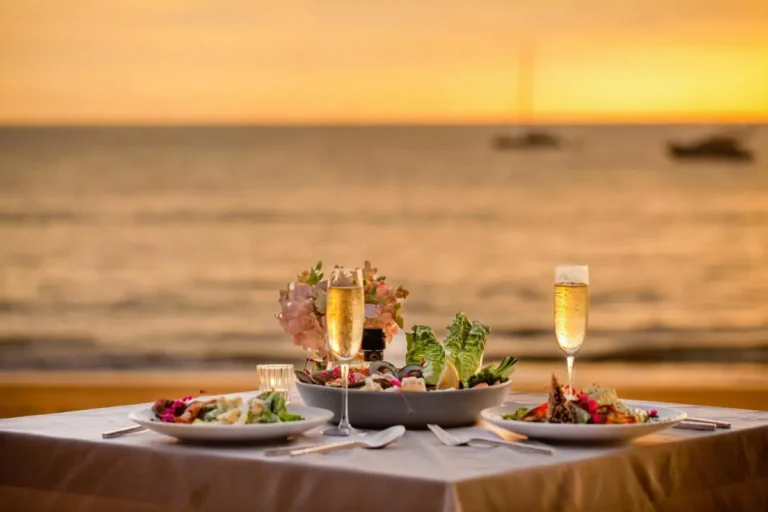 Romantic Beachside Dinner Setup at Sunset Over Calm Ocean Waters Romantic Beachside Dinner Setup at Sunset Over Calm Ocean Waters