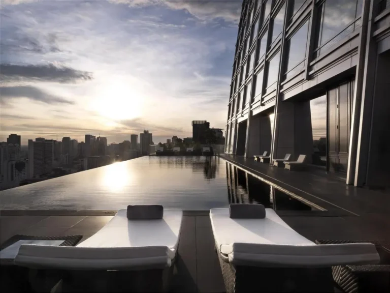Rooftop Infinity Pool and Lounge Area Overlooking Pathumwan City Skyline at Sunset
