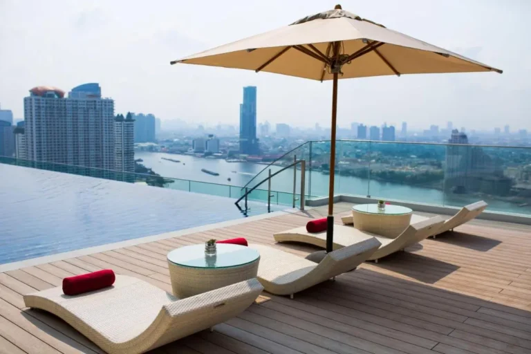 Rooftop Infinity Pool and Lounge Area Overlooking Thonburi Cityscape and River Views