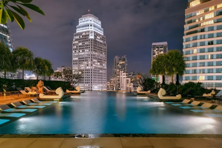 Rooftop Infinity Pool with Submerged Loungers and Urban Night Skyline in Wattana Bangkok