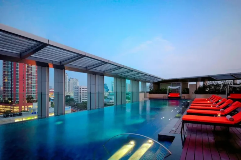 Rooftop Infinity Pool with Wooden Deck and Red Lounge Chairs in Wattana Bangkok