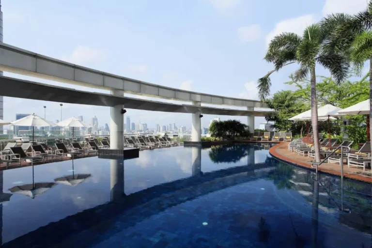 Rooftop Pool Area with Lounge Chairs and Urban Skyline View in Pathumwan Bangkok