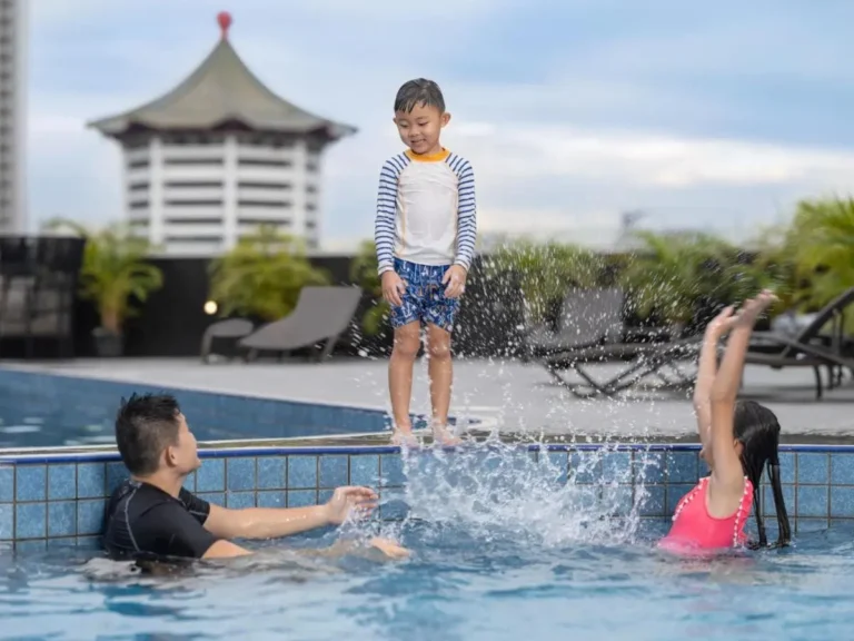 Rooftop Swimming Pool Area with Lounge Chairs and Children Playing in Orchard