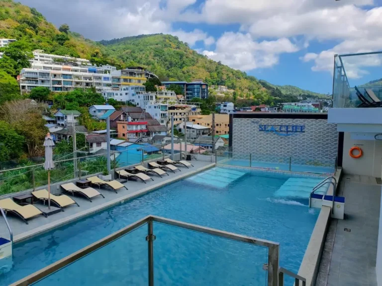 Rooftop Swimming Pool Area with Lounge Chairs and Panoramic Hillside Views in Patong Beach