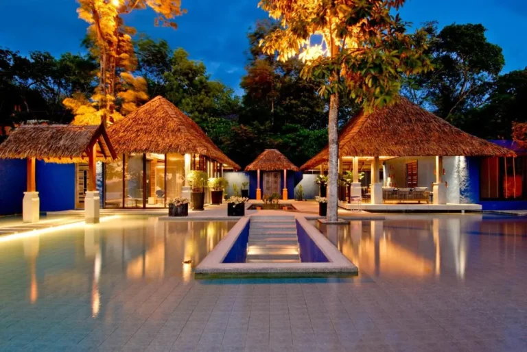 Tranquil Outdoor Pool Area with Thatched Pavilions and Ambient Lighting at Panwa Beach