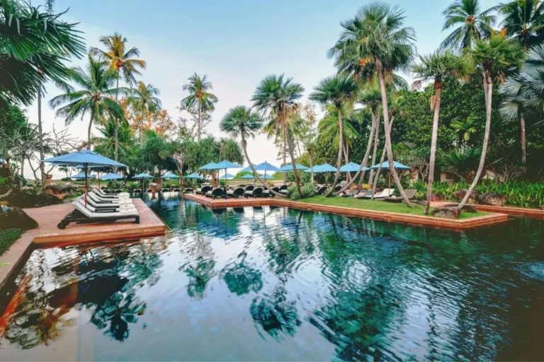 Tropical Outdoor Swimming Pool Area with Lounge Chairs and Ocean View at Mai Khao Beach